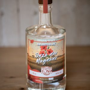 Bouteille de spiritueux "Onze des Magnans" de la distillerie Onze, posée sur une table en bois.