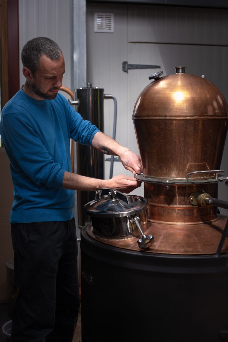 Marien Beaugrand, fondateur de la distillerie Onze, en train de travailler sur un alambic en cuivre dans son atelier de distillation.