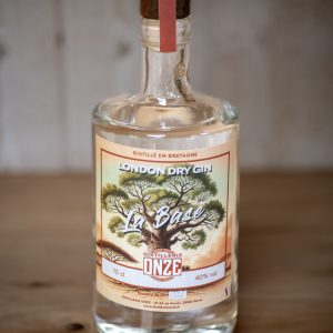 Bouteille de gin London Dry Gin "La Base" de la distillerie Onze, posée sur une table en bois.