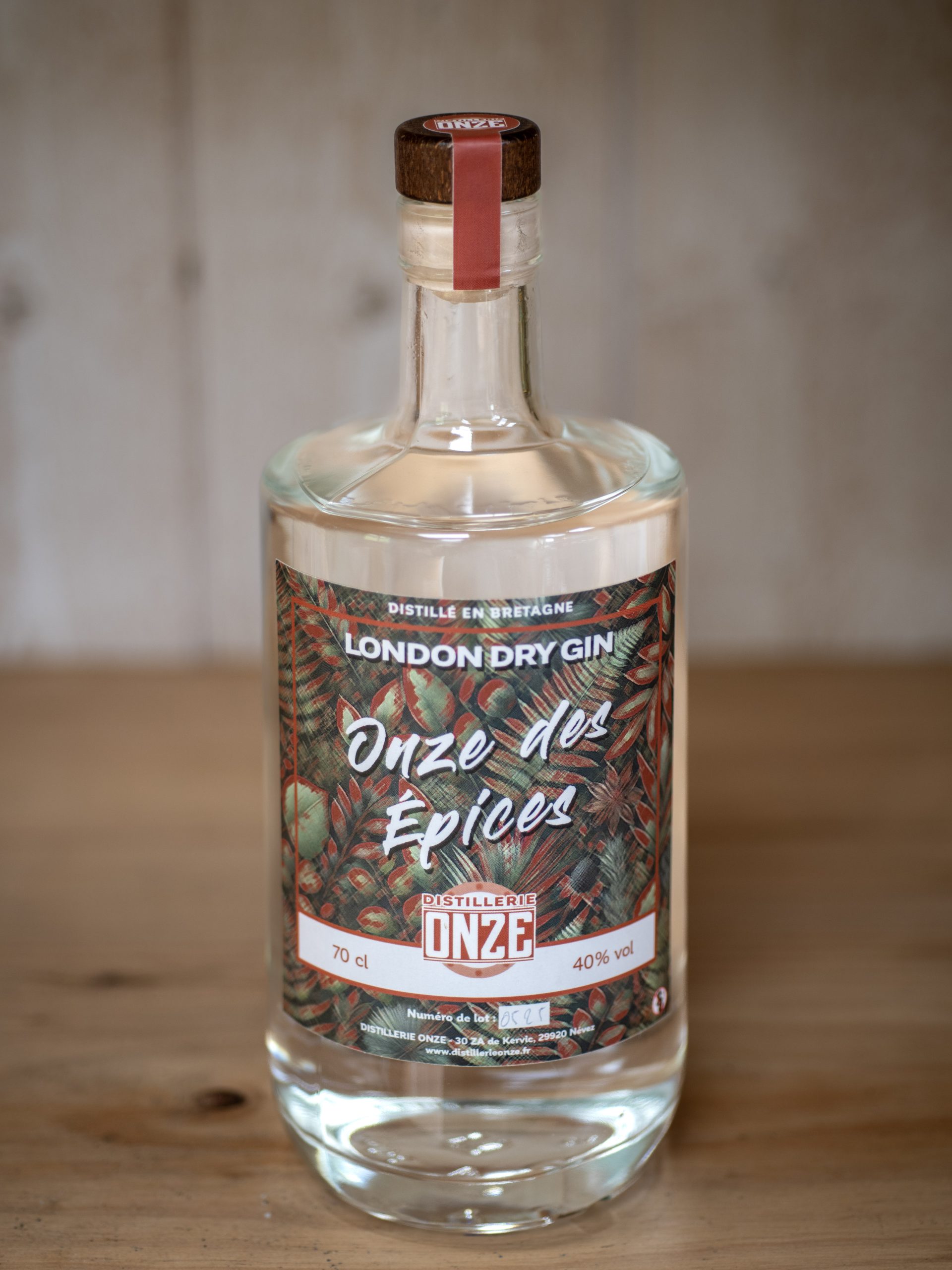 Bouteille de gin London Dry Gin "Onze des Épices" de la distillerie Onze, posée sur une table en bois.