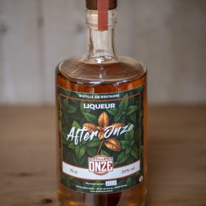 Bouteille de liqueur "After Onze" de la distillerie Onze, posée sur une table en bois.