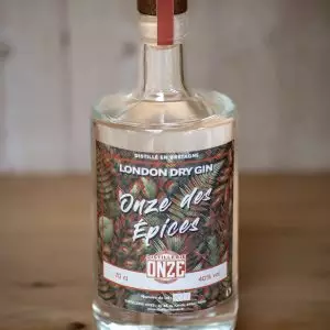 Bouteille de gin London Dry Gin "Onze des Épices" de la distillerie Onze, posée sur une table en bois.